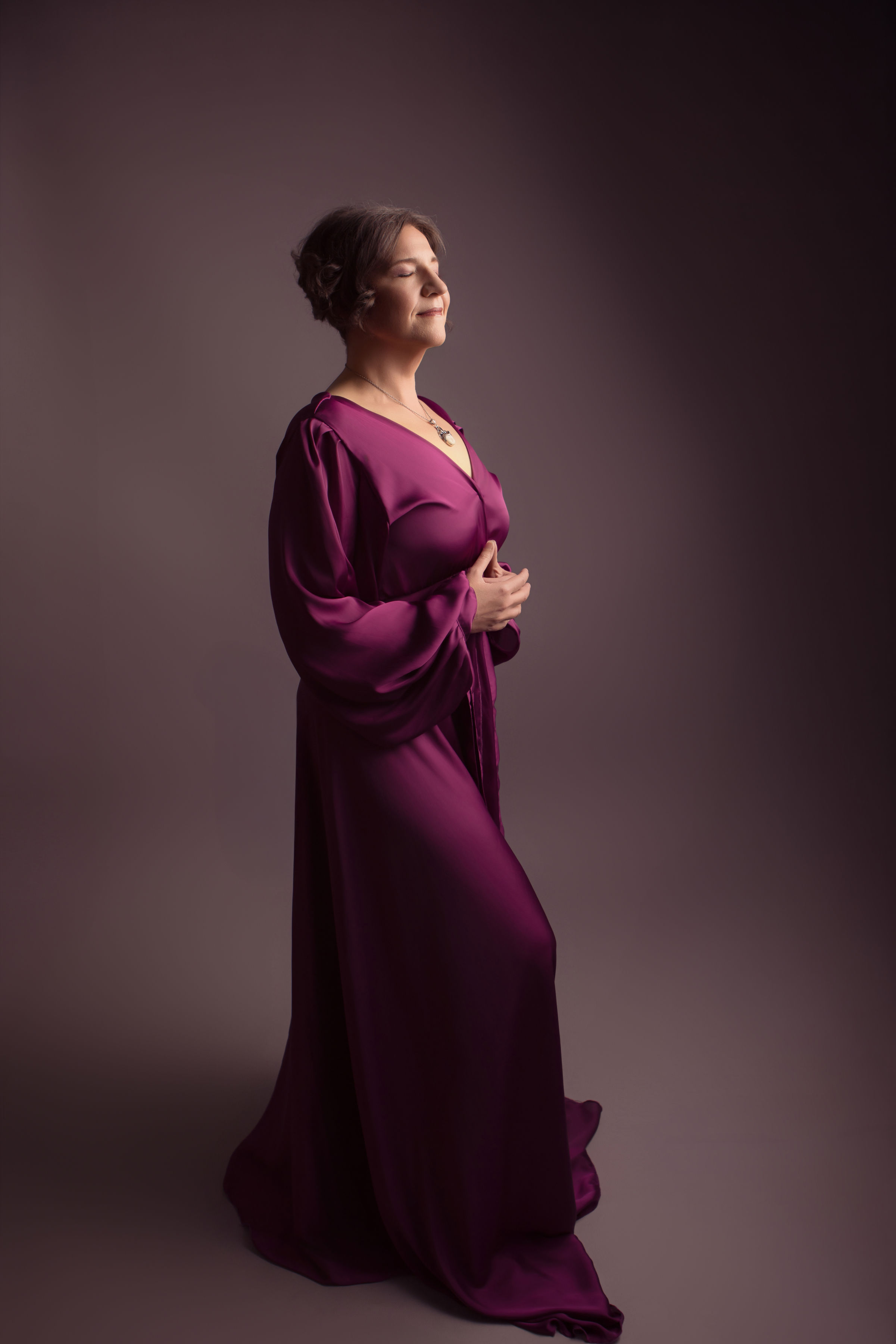 Mandy Kuelz in a flowing plum gown, eyes closed in a peaceful, meditative moment